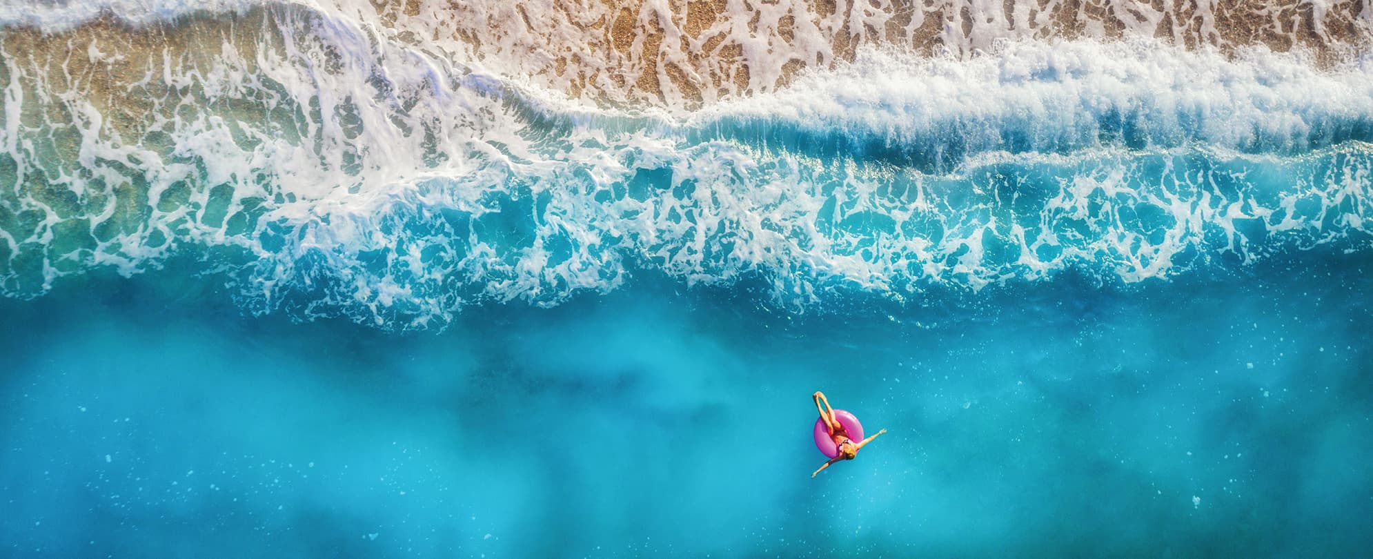 Woman laying on top of a pink float in the ocean 